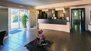 A modern reception area with a reception desk, a potted plant, and a seating area with a coffee table. - Bolgheri Marina Resort ex Varo Village (Bibbona)
