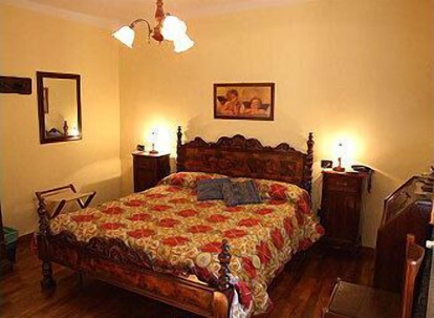 Un dormitorio con una cama de madera, dos mesitas de noche con lámparas, un espejo y un cuadro en la pared.