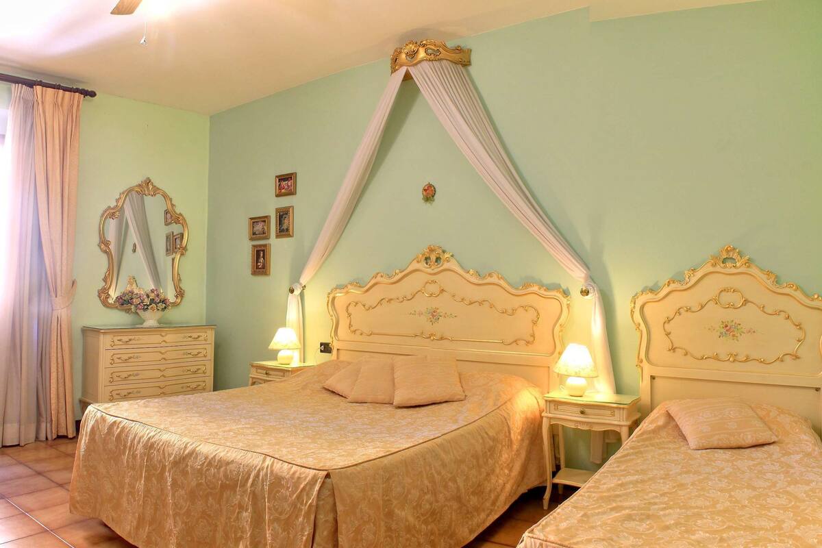 Ein Schlafzimmer mit zwei Betten, einem Schminktisch mit Spiegel und einem Himmelsbett.