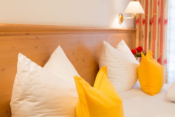 A bed with white and yellow pillows, a wooden headboard, and a wall-mounted lamp.
