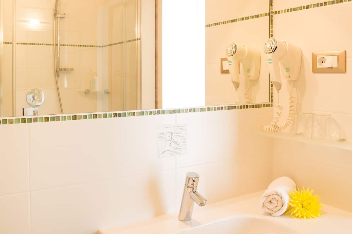 A bathroom with a sink, mirror, and a shower.