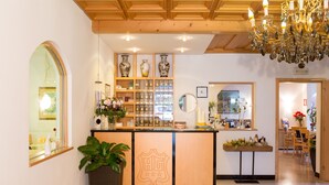 Una zona de recepción con un mostrador de madera, un candelabro y una exhibición de jarrones y plantas.