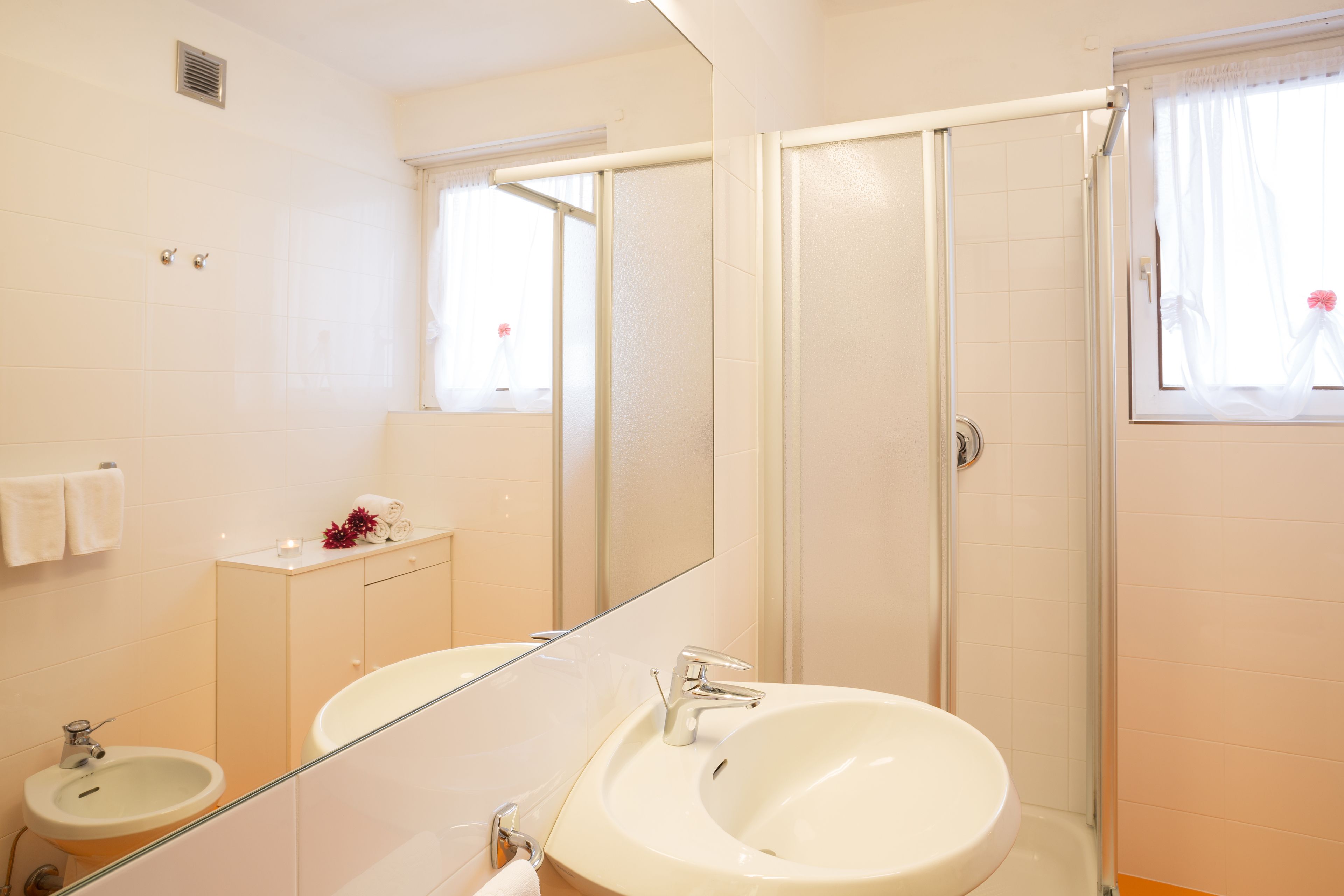 A bathroom with a sink, mirror, and shower.