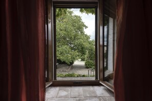 A view through an open door to a garden with trees and a gravel path. - Agriturismo La Palazzina (Murlo)