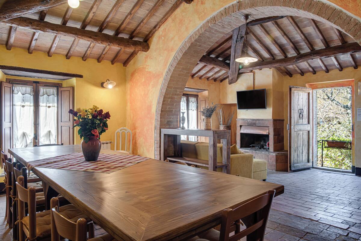 A rustic dining area with a wooden table, chairs, and a vase of flowers.