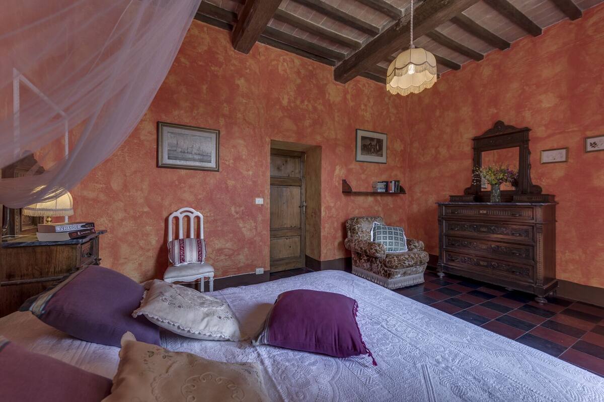 A bedroom with a bed, a chair, a dresser, and a door.