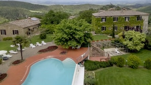 A large building with a swimming pool, surrounded by lush greenery and hills in the background. - Agriturismo La Palazzina (Murlo)
