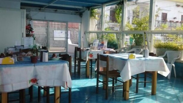 Un área de comedor al aire libre con mesas cubiertas de manteles blancos, sillas de madera y techo azul.