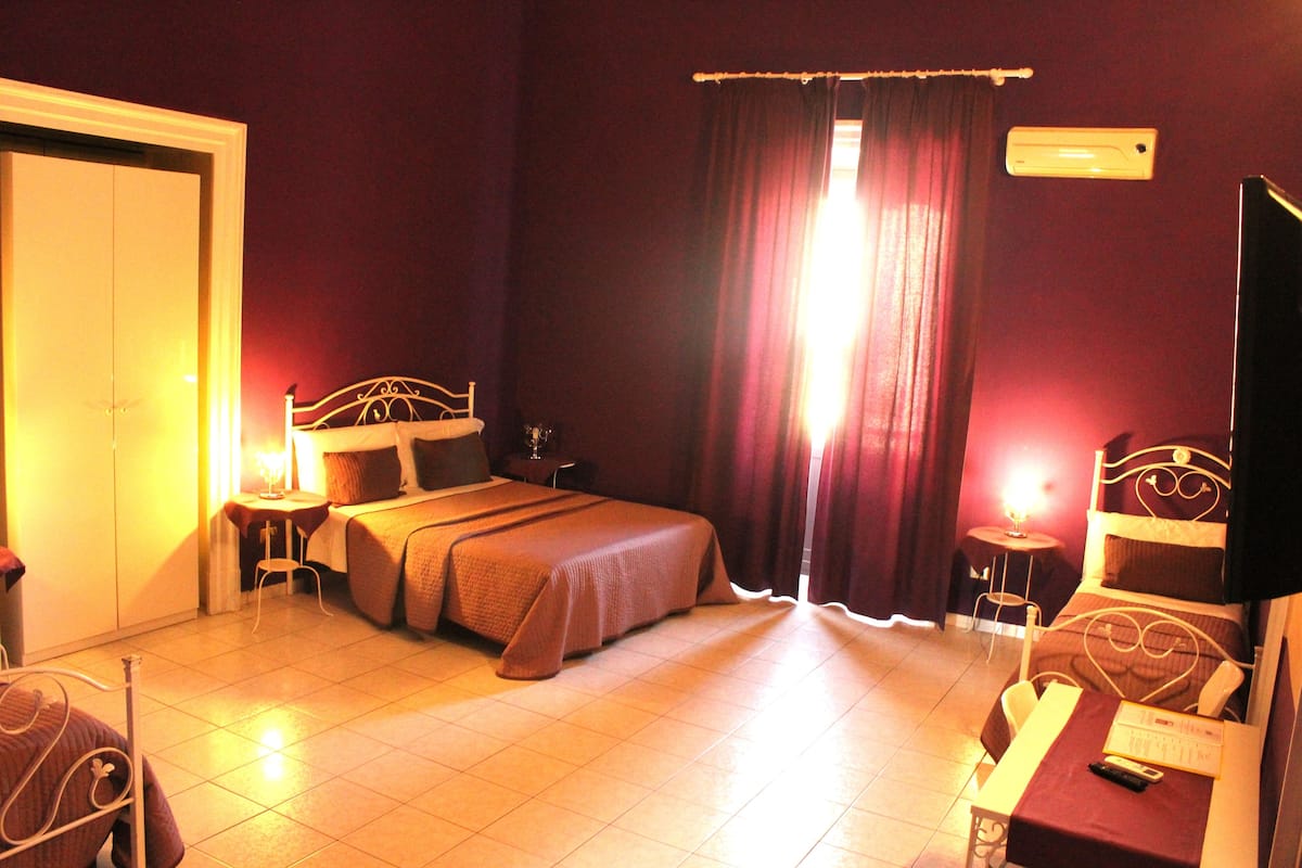 A hotel room with a bed, bedside tables, a desk, a chair, and a television.