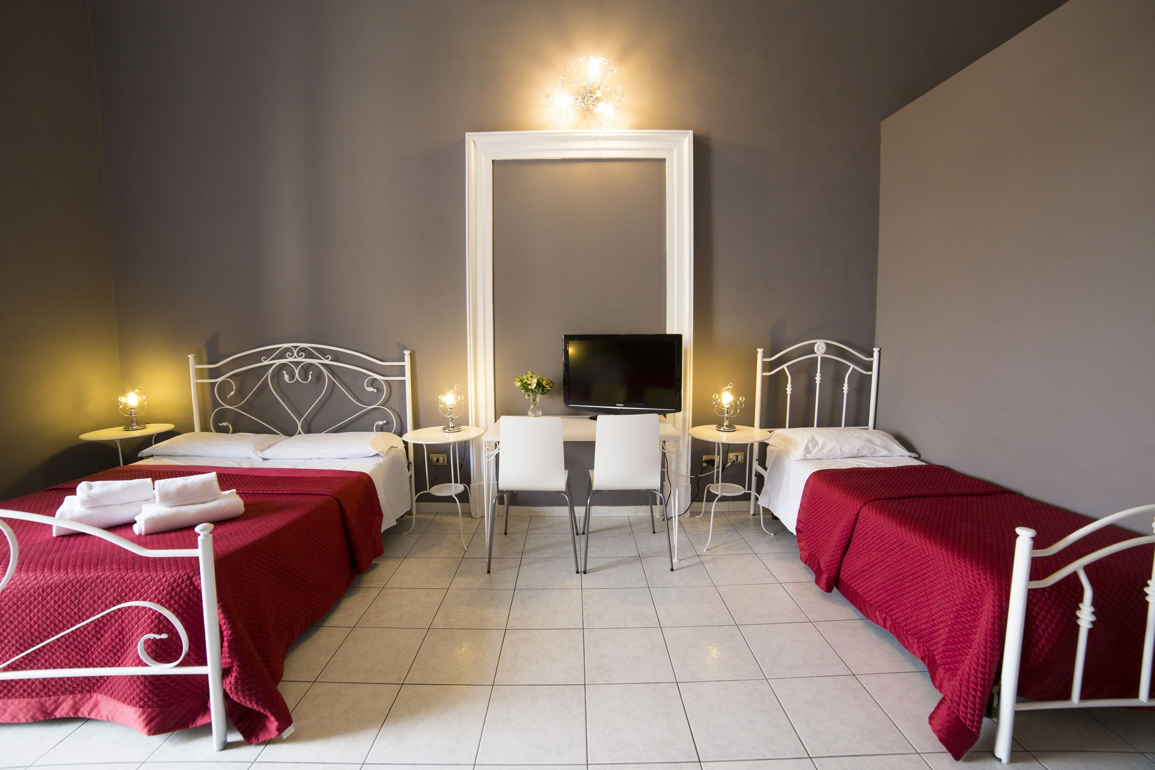 Une chambre d’hôtel avec deux lits, un bureau, une télévision et deux tables de chevet avec des lampes.