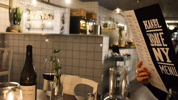 A restaurant interior with a menu, a bottle of wine, and a glass of red wine on the table.
