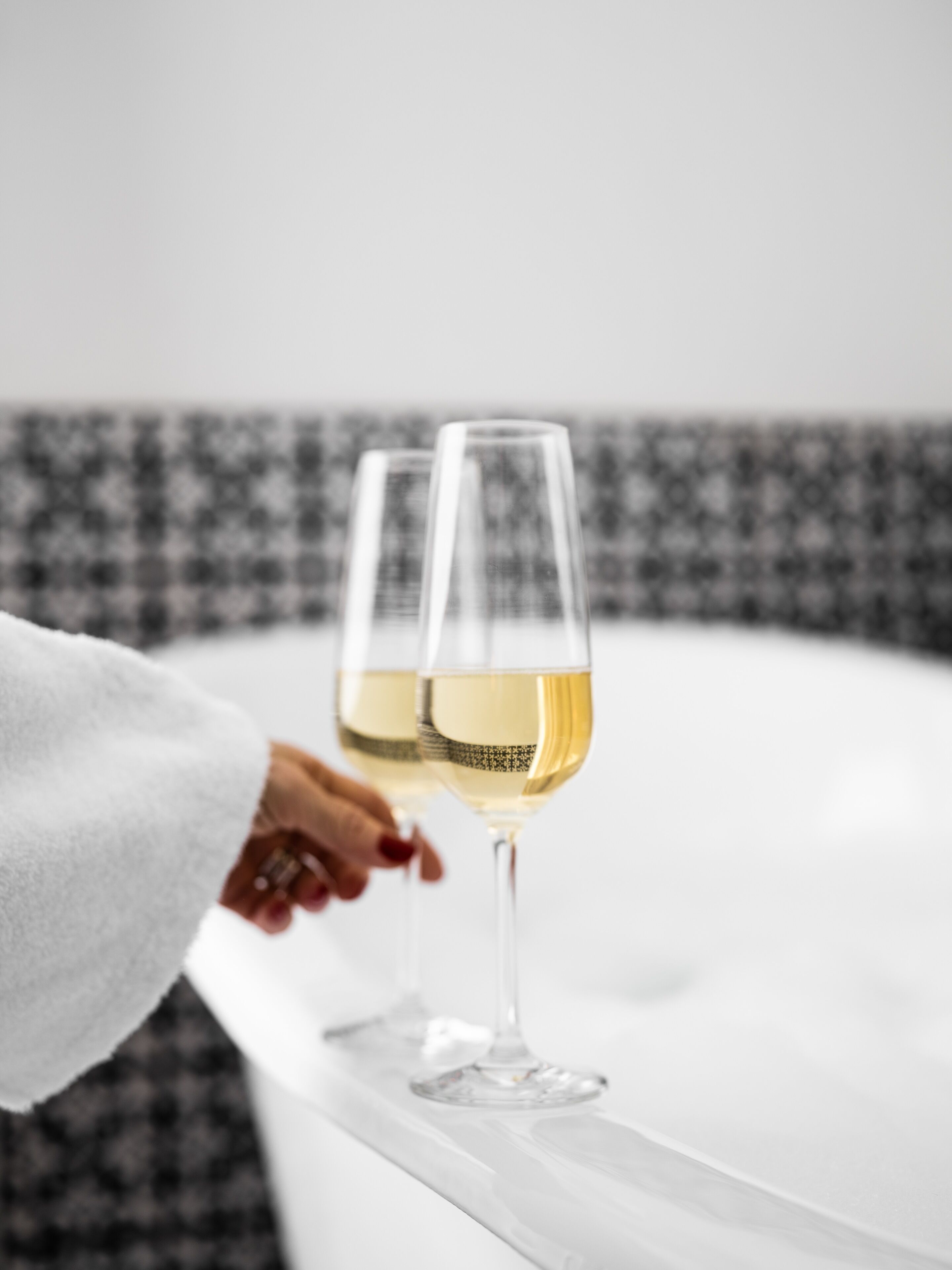 Zwei Gläser Weißwein auf einer weißen Oberfläche mit kariertem Hintergrund.