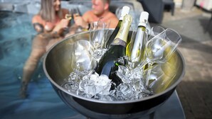 A hot tub with a metal bowl containing champagne bottles and glasses.