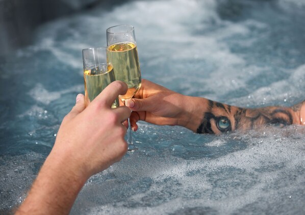 Two people holding glasses of a yellowish liquid, likely champagne, in a hot spring with visible bubbles. - Huskvarna Stadshotell (Huskvarna)