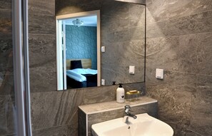 A modern bathroom with a large mirror, a sink, and a shower area. - Huskvarna Stadshotell (Huskvarna)