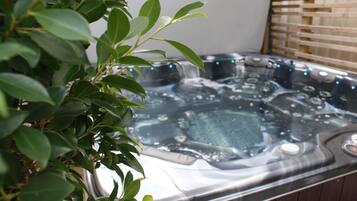 Un jacuzzi con una terraza de madera y una planta al frente.