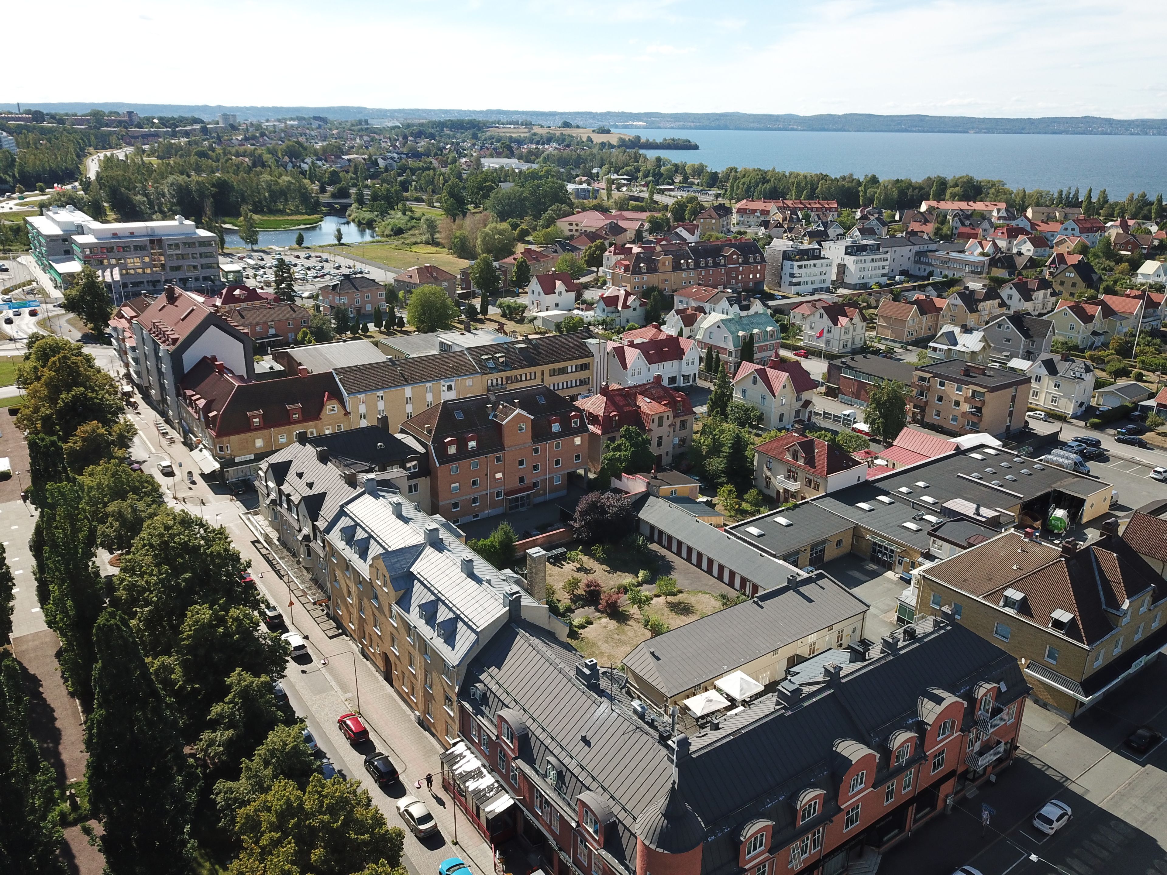 An aerial view of a residential area with buildings, roads, and a body of water in the background.
