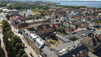 Ovenudblik over et boligområde med bygninger, veje og et vandareal i baggrunden.