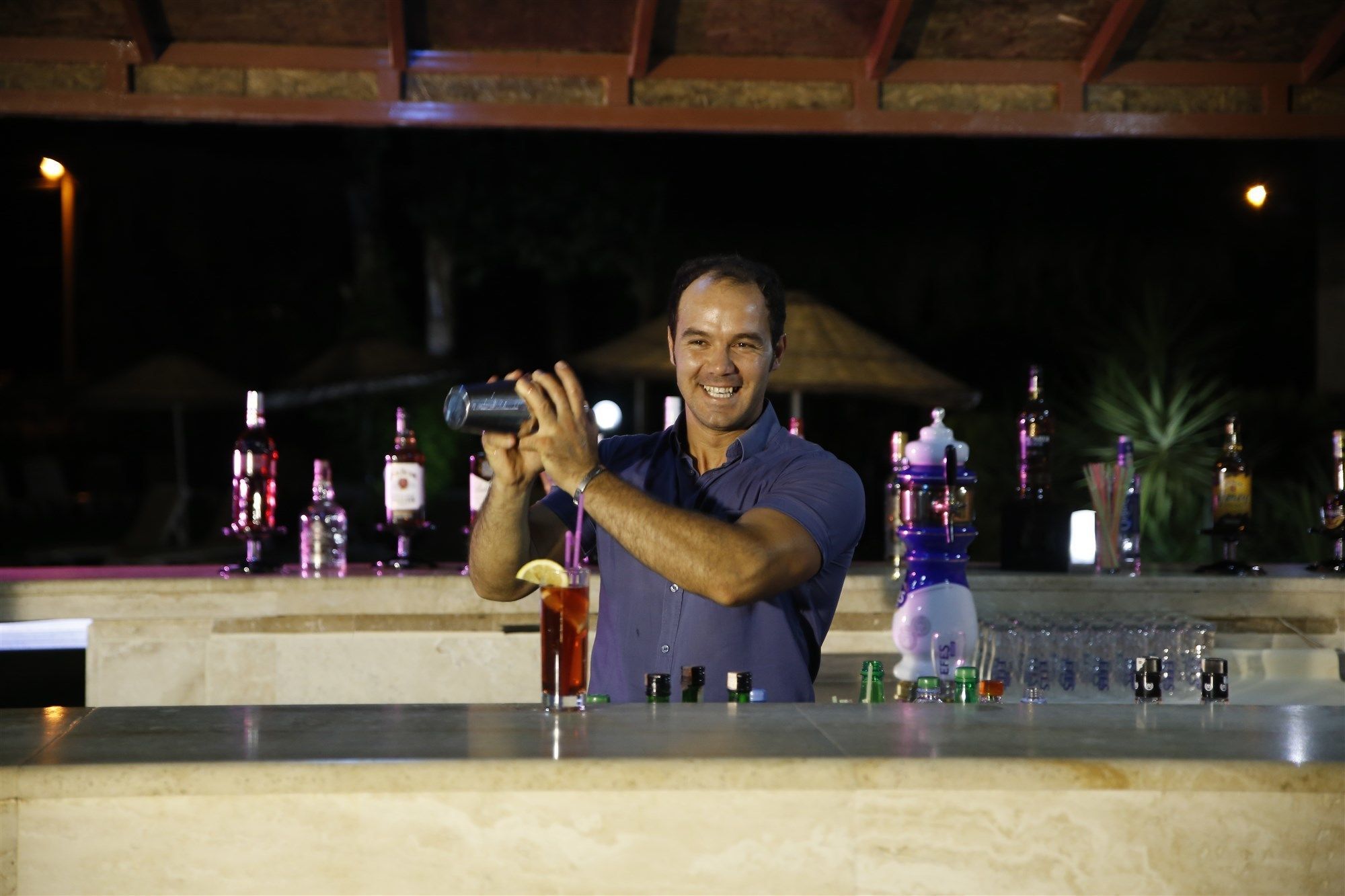 Ein Barkeeper hinter einer Bar mit verschiedenen Flaschen und Gläsern.