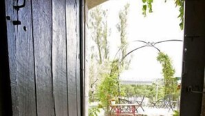 An entrance with a stone-tiled floor and a metal door. - Moulin de la Camandoule (Fayence)