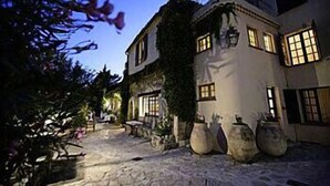 A traditional building with a courtyard, stone flooring, and large vases. - Moulin de la Camandoule (Fayence)