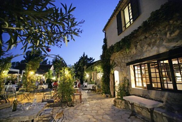 An outdoor patio area with stone flooring, tables, and chairs. - Moulin de la Camandoule (Fayence)
