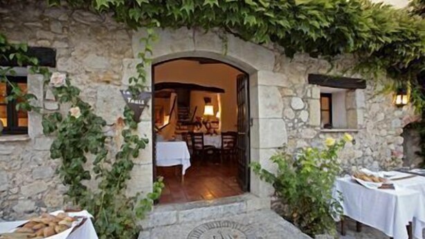 A stone building with a doorway leading to an interior dining area. - Moulin de la Camandoule (Fayence)