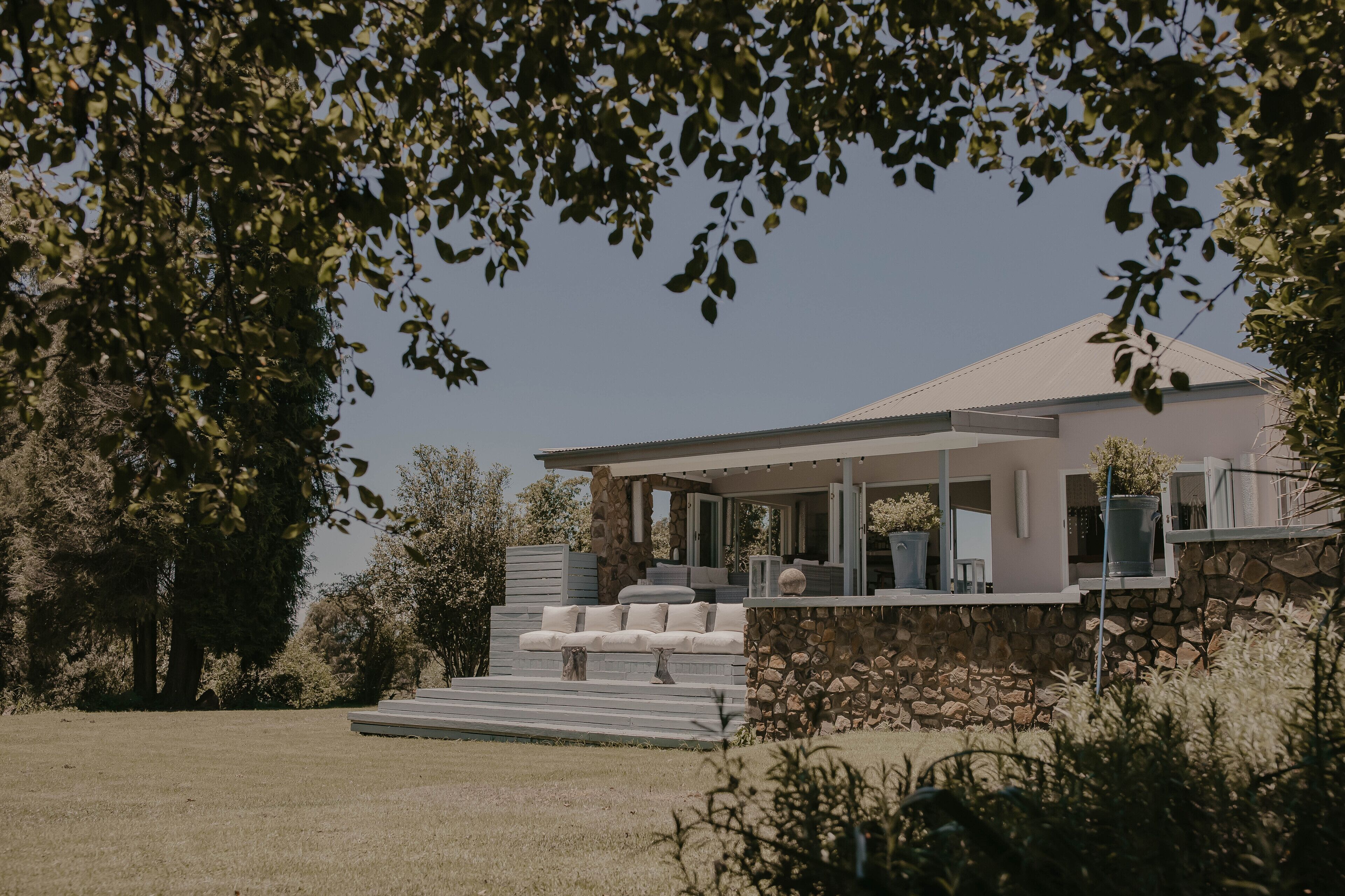 Une maison moderne avec une façade en pierre, un porche abrité et une cour gazonnée.