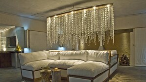A modern living room with a large sectional sofa, a wooden coffee table, and a hanging chandelier.