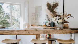 A kitchen with a wooden island, bar stools, and a vase with flowers.
