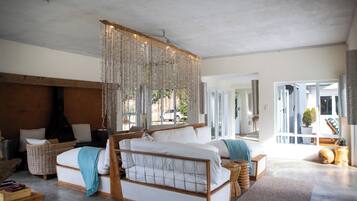 Une chambre spacieuse avec un grand lit, un luminaire suspendu et une vue sur l’extérieur.