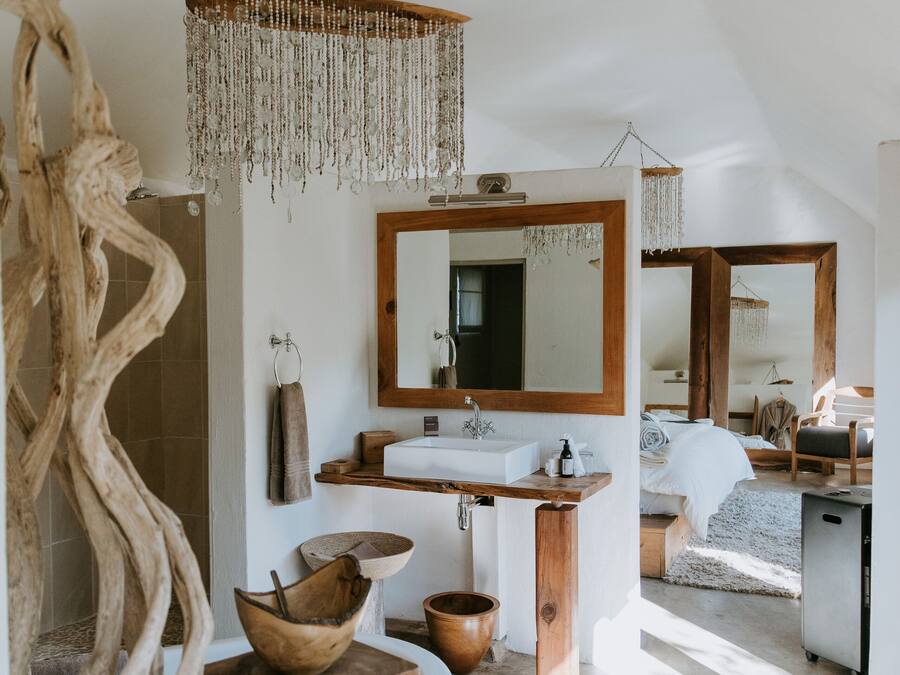 A modern bathroom with a wooden vanity, a large mirror, and a hanging chandelier.