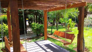 A wooden swing set in a garden with a paved walkway and lush greenery. - Praia Sol Hotel (Santa Terezinha do Itaipu)