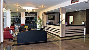A hotel lobby with a reception desk, seating area, and a restaurant sign. - Praia Sol Hotel (Santa Terezinha do Itaipu)