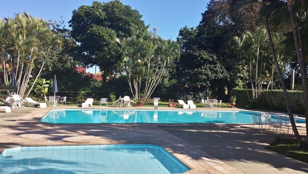 A pool area with lounge chairs and tables, surrounded by palm trees and greenery. - Praia Sol Hotel (Santa Terezinha do Itaipu)