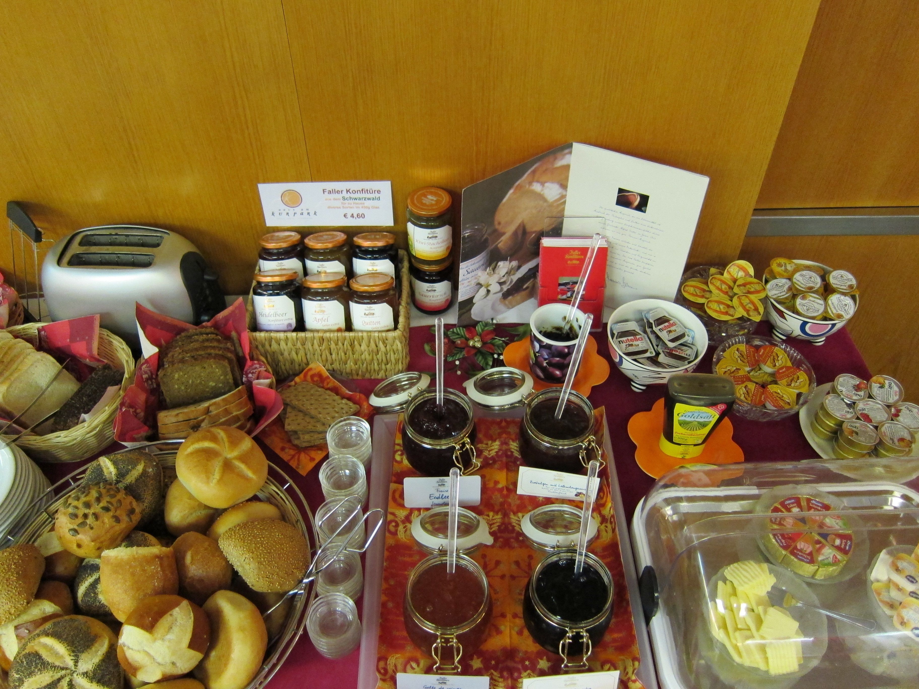 A buffet table with various food items including breads, pastries, and condiments.