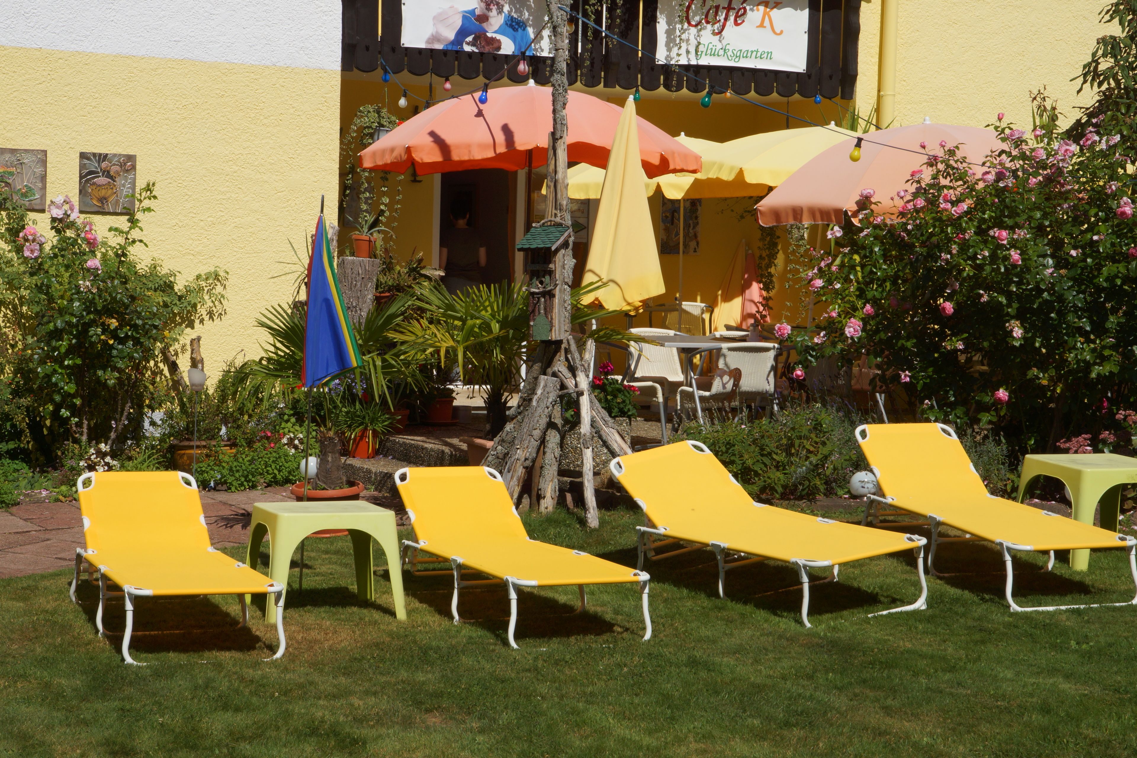 Een terras met gele loungestoelen, een tafel en parasols.
