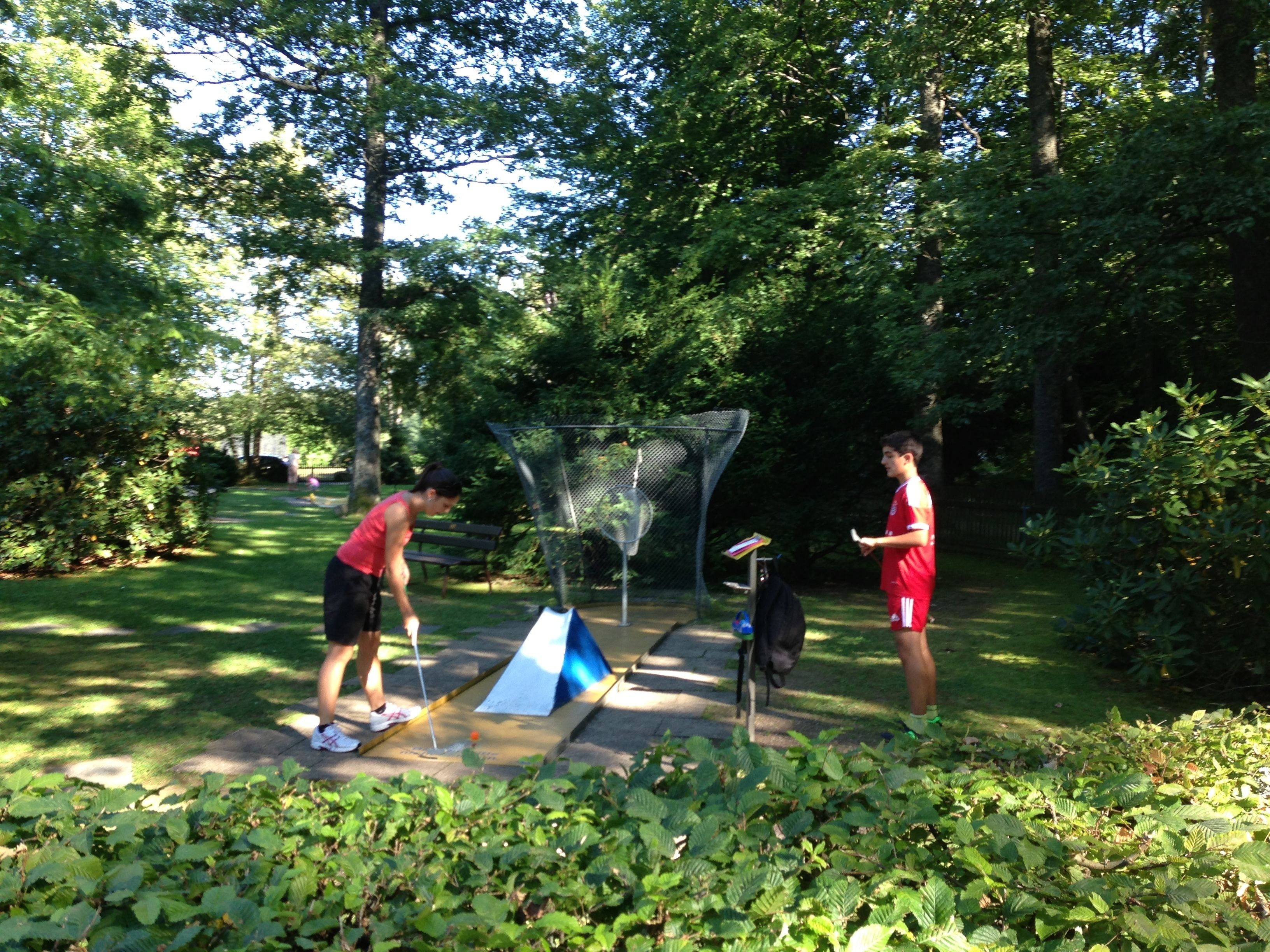 Un parc avec un filet de badminton, une petite table et de la verdure.