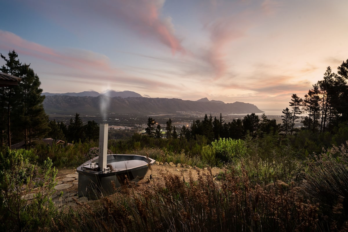 A hot tub in a natural setting with mountains in the background.