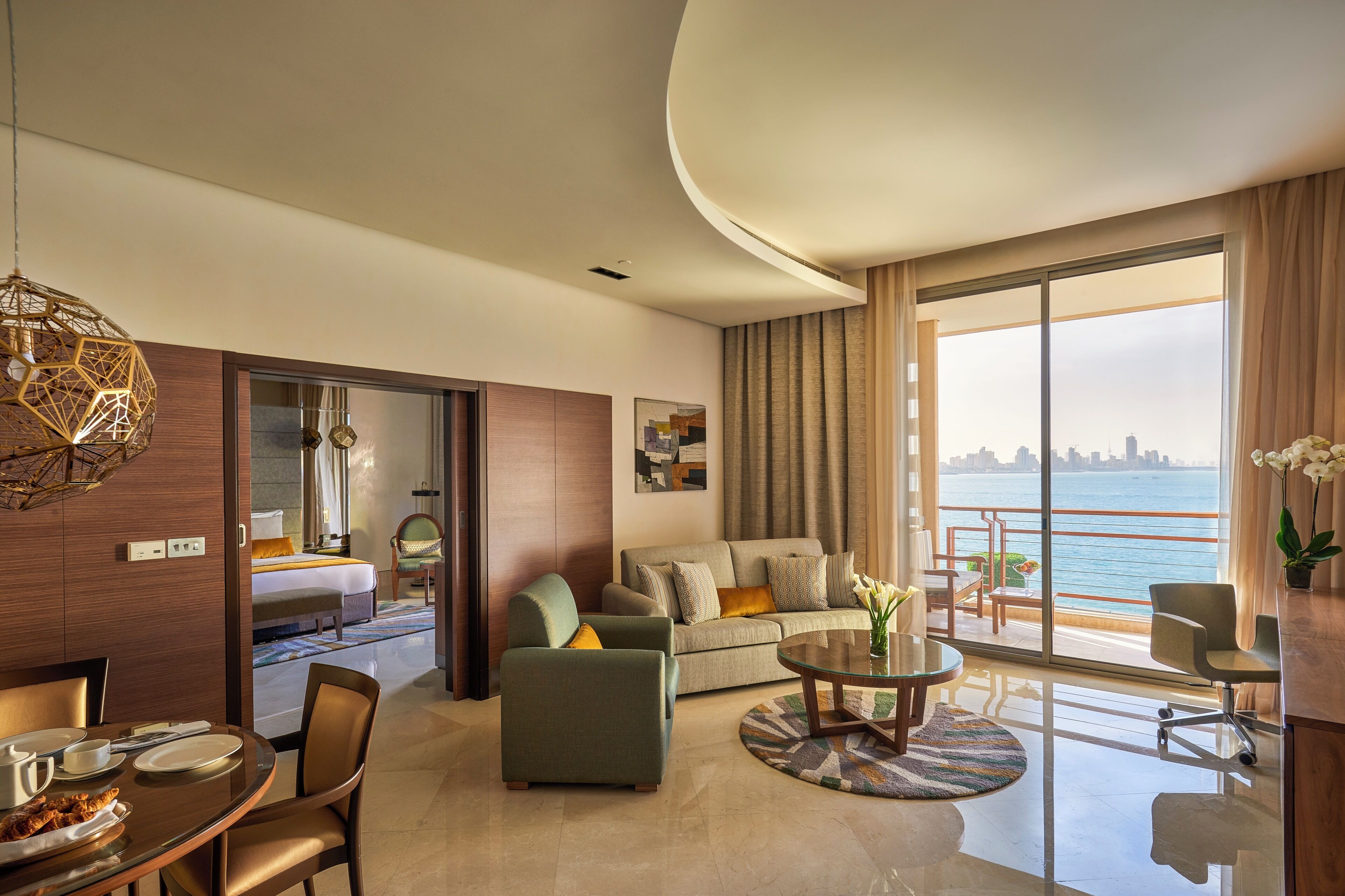 Una habitación de hotel moderna con balcón, zona de comedor y sala de estar.