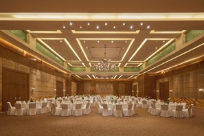 A large banquet hall with multiple round tables set for events, featuring a modern ceiling design with recessed lighting and a central chandelier. - Marina Hotel Kuwait (Salmiya)