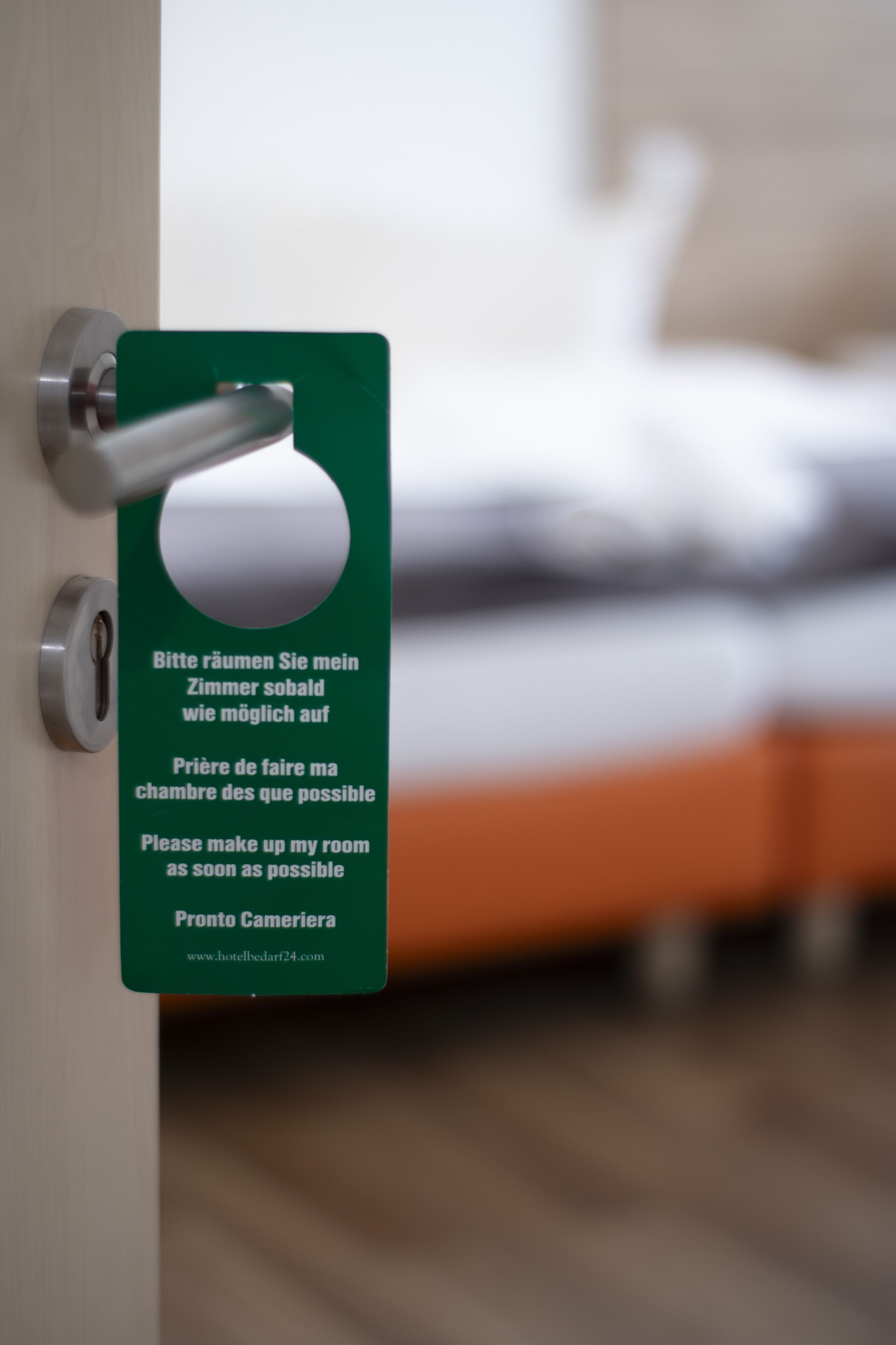 Une porte de chambre d’hôtel avec une pancarte demandant aux clients de ranger leur chambre dès que possible.