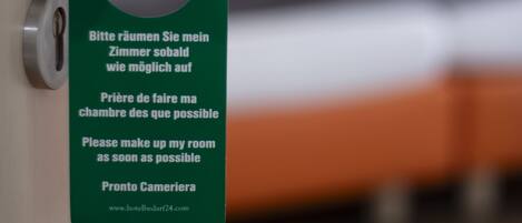 Puerta de una habitación de hotel con un cartel solicitando a los huéspedes que dejen la habitación cuanto antes.