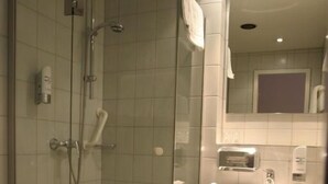 A bathroom with a glass-enclosed shower, a sink, and a mirror. - Krokodil Restaurant & Hotel (Heidelberg)