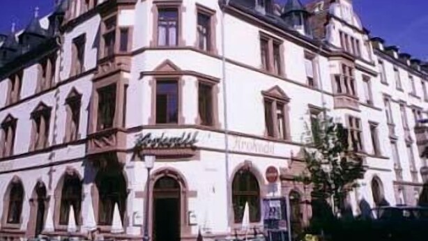 A historic building with a corner entrance, arched windows, and a sign that reads "Hotel". - Krokodil Restaurant & Hotel (Heidelberg)