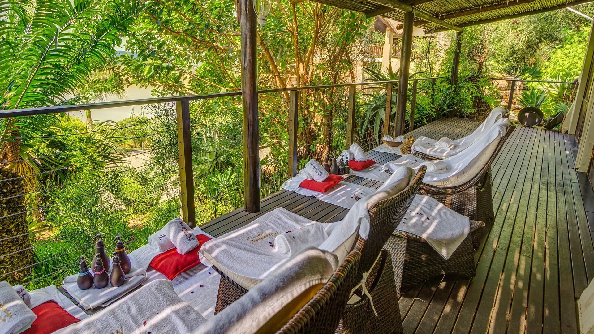 A covered outdoor seating area with wicker furniture, white towels, and red pillows.