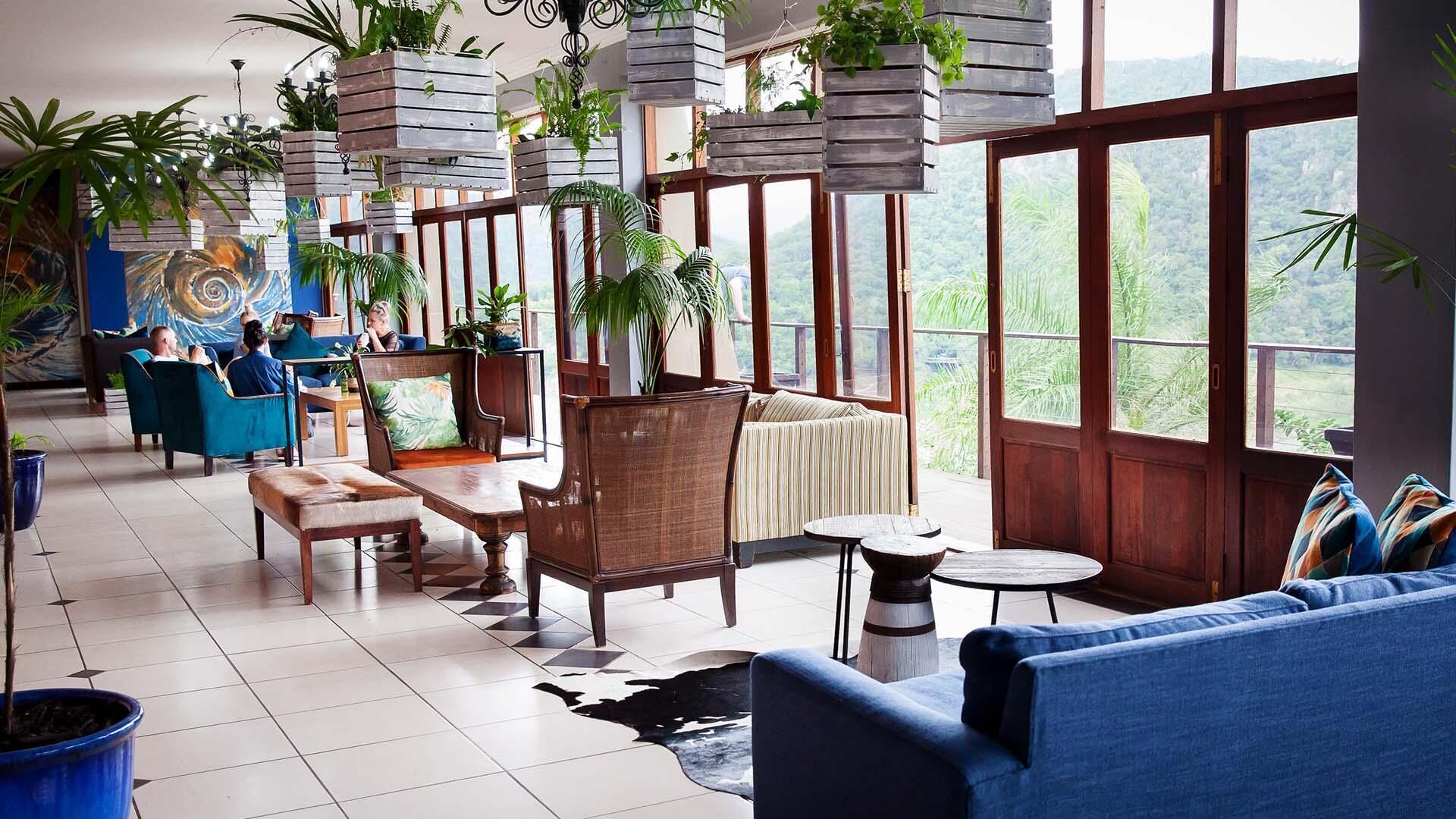Un salon spacieux doté de grandes fenêtres, de meubles en bois et de jardinières suspendues.