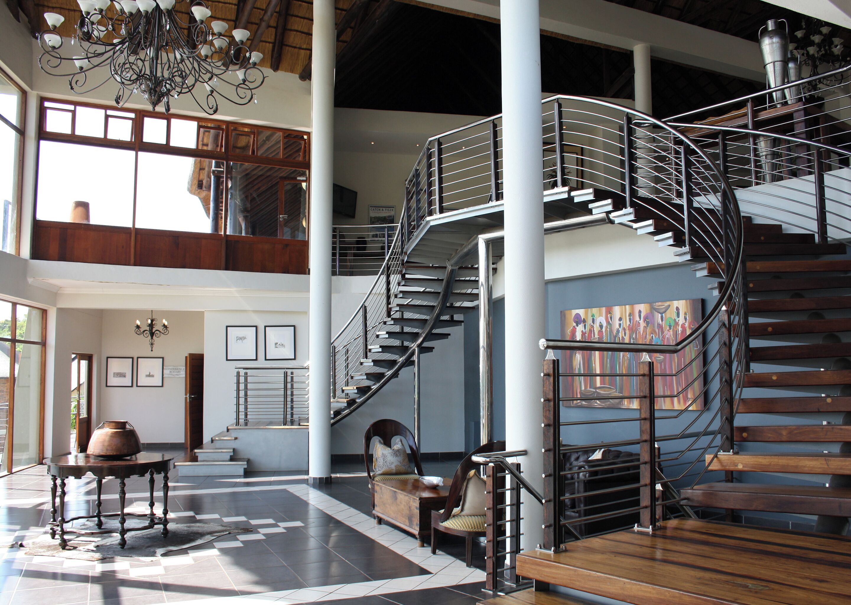 A spacious lobby with a grand staircase, large windows, and a chandelier.