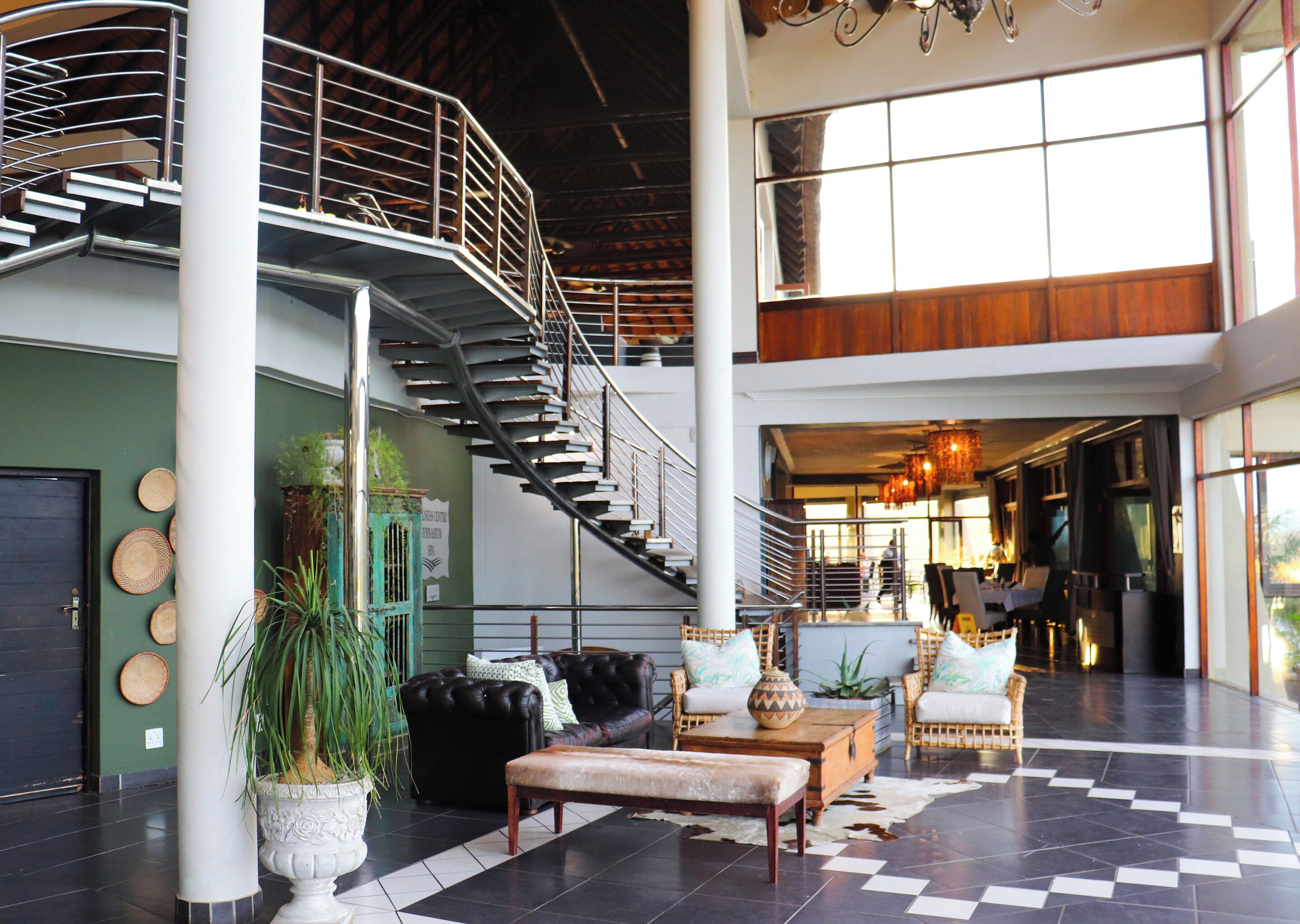 Un lobby amplio con una escalera central, zona de estar y ventanas grandes.