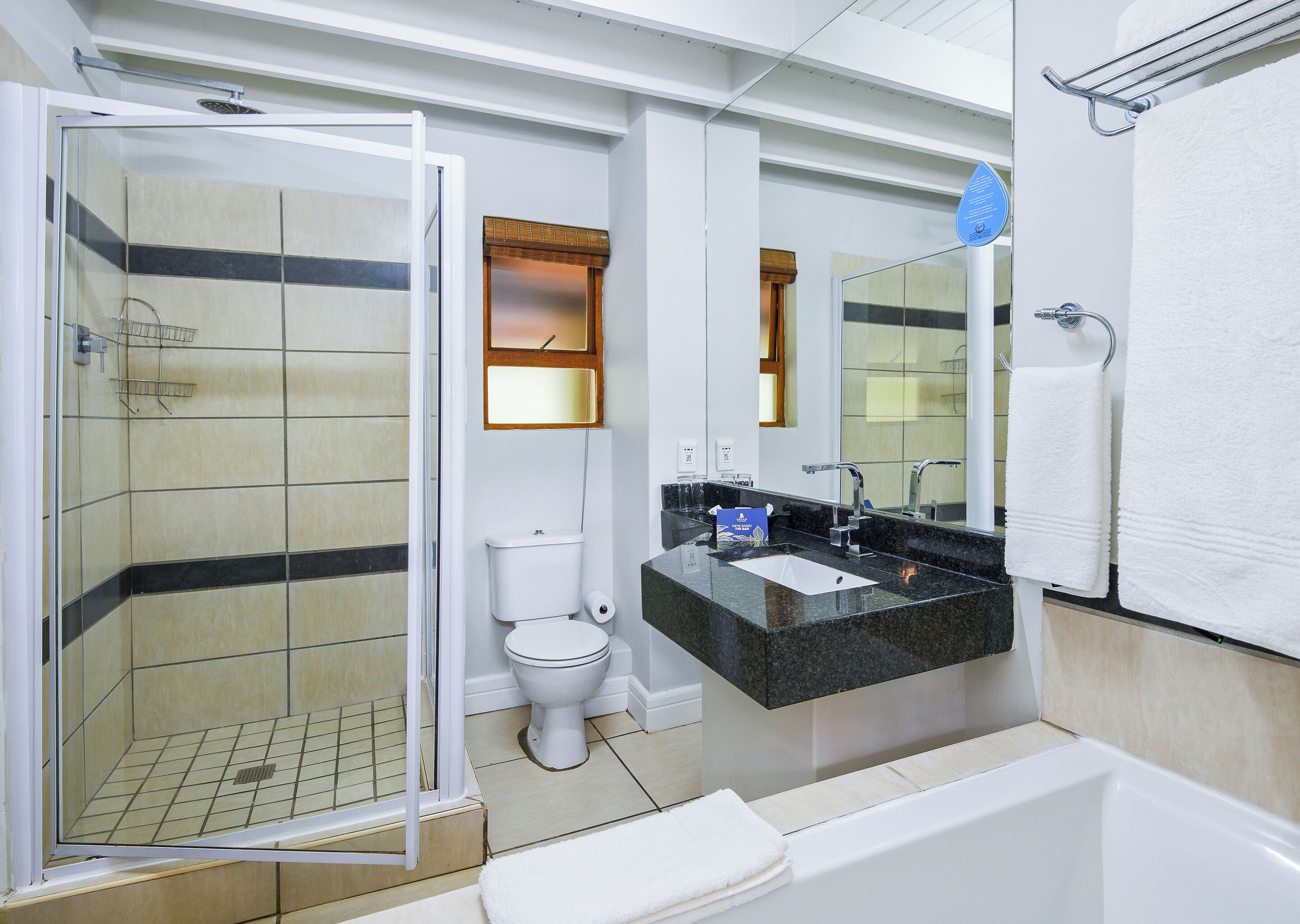 Ein modernes Badezimmer mit einer Glasdusche, einer Toilette, einem Waschbecken mit Spiegel und einer Badewanne.
